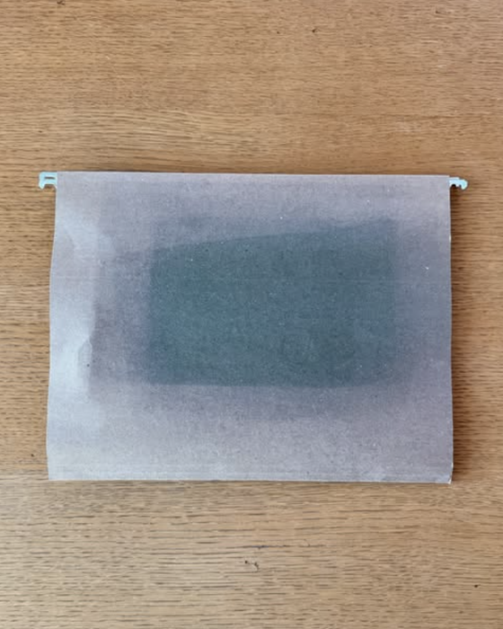 Translucent parchment gently covers a dark rectangular object resting on a wooden surface