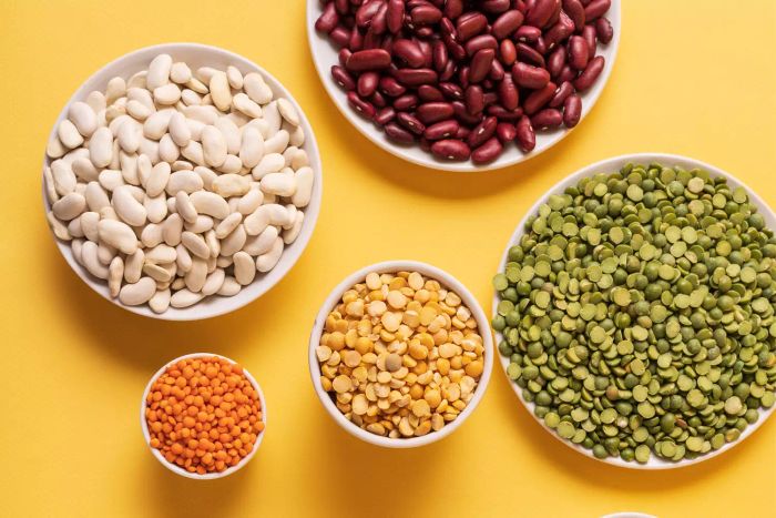 Aerial view of a variety of peas, lentils, beans, and legumes on a yellow background
