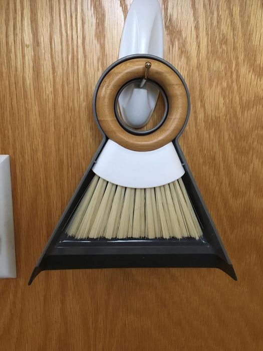 A reviewer's mini dustpan and broom hanging on a hook.