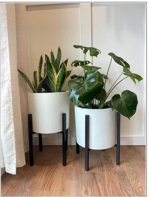 A customer demonstrates two white pots on sleek black stands.