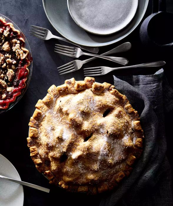 A rich brown butter and vanilla pear pie displayed on a dark gray table setting