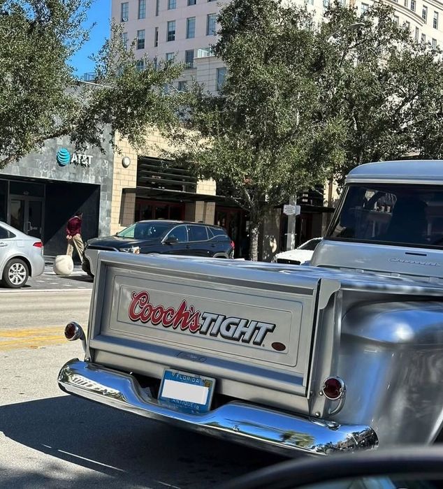 A classic truck with a tailgate sign reading 