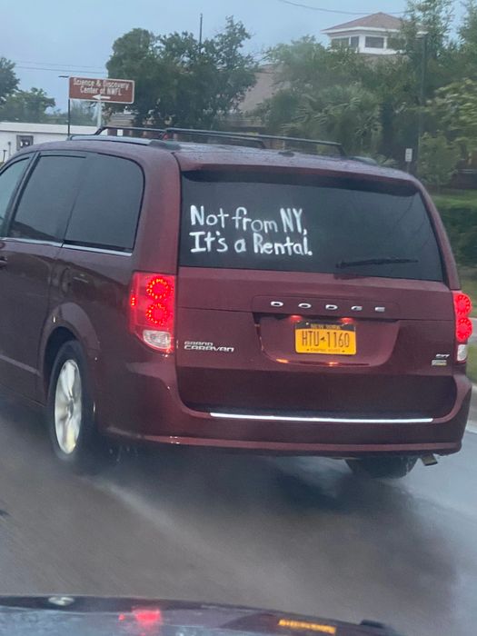 The back of a minivan displays a sign that reads 
