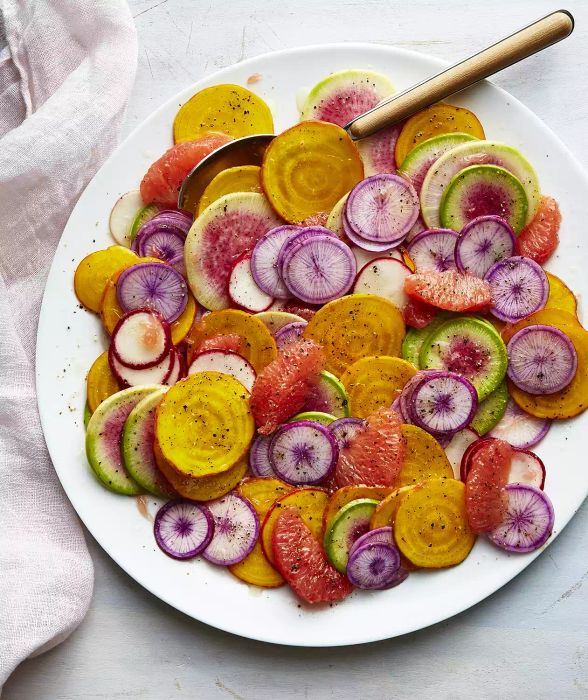 Grapefruit, Beet, and Radish Salad Served on a Large Round Plate With a Serving Spoon