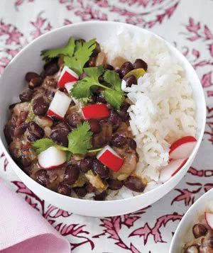 Cuban Black Beans and Rice garnished with diced radishes and cilantro, served in a white bowl.