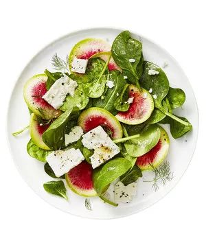 Spinach and radish salad with feta served on a white plate