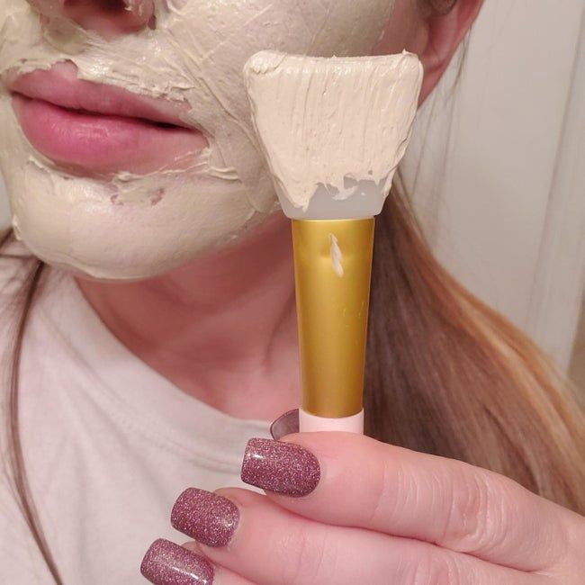 Reviewer holding a spatula up to their face, ready to apply the mask.