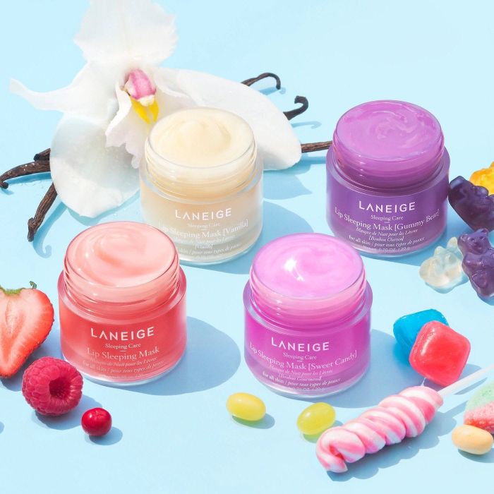 The lip masks in all four available scents, surrounded by candy and fruit.