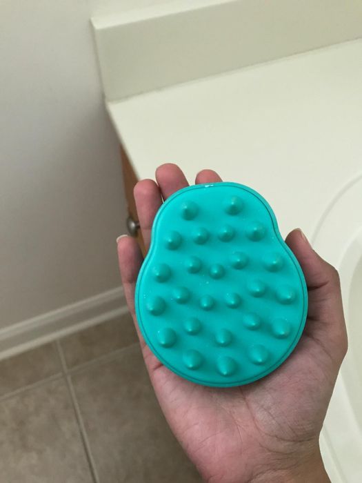 Reviewer holding the teal-colored massaging brush.