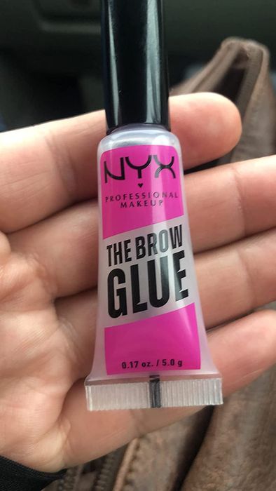 a reviewer holding the glue, showing it's about the size of a lip gloss tube