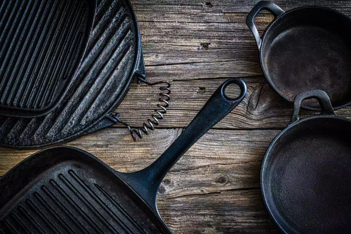 Four cast-iron pans and grills arranged on a dark brown wooden surface