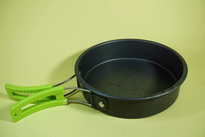 A detailed close-up of a cast-iron skillet set against a green background