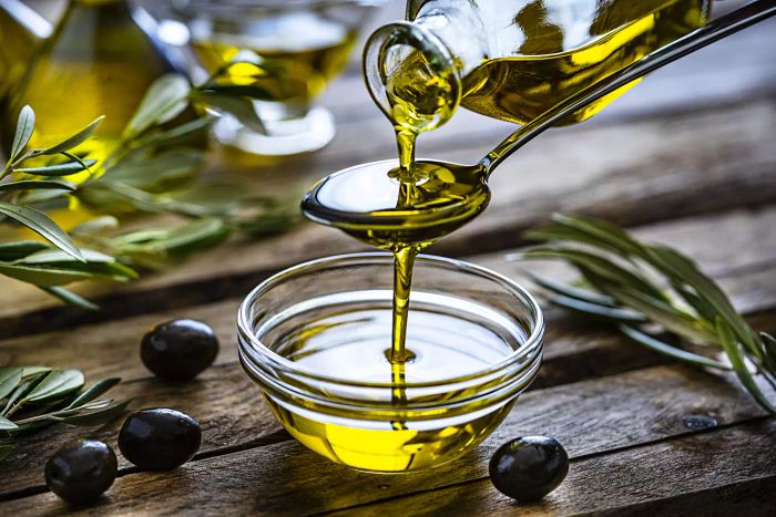 Olive oil being drizzled from a spoon into a small bowl