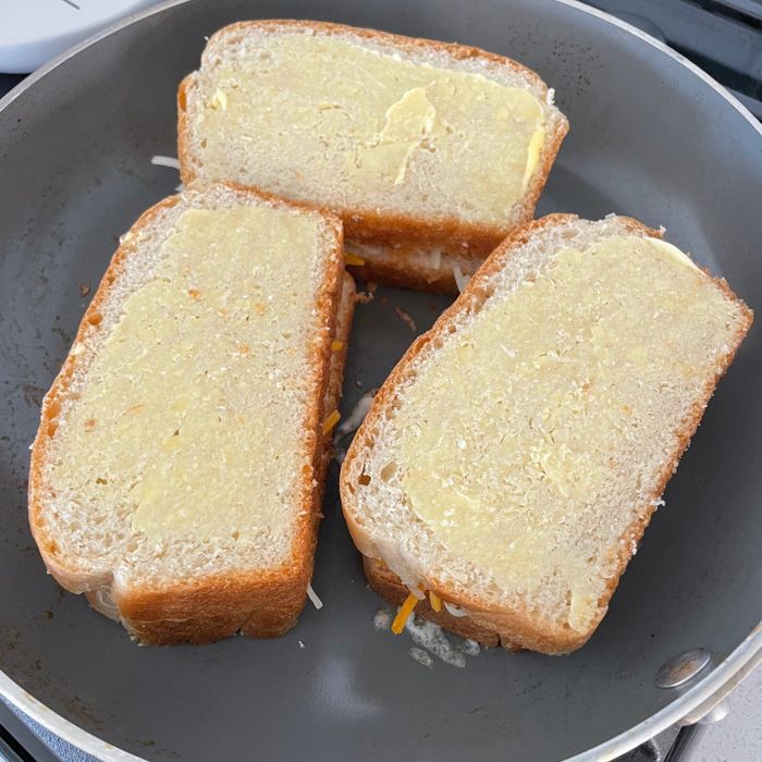 Grilled cheese sandwiches sizzling in a pan.