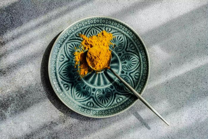 A spoonful of turmeric resting on a blue plate