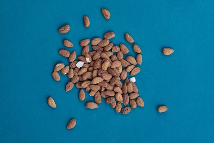A handful of almonds scattered on a blue background