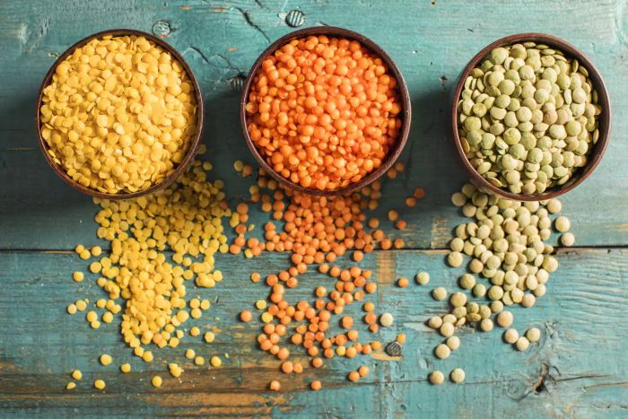 Cups filled with yellow, red, and green lentils arranged side by side