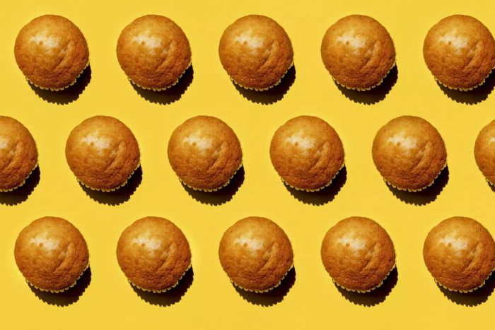 A row of muffins set against a yellow background