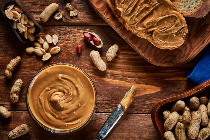 A jar of peanut butter surrounded by peanuts, viewed from above