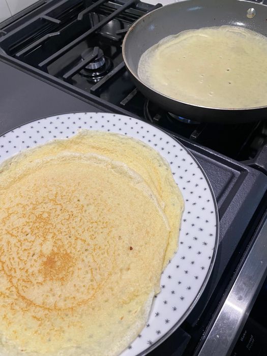 Crepes cooking in a pan.