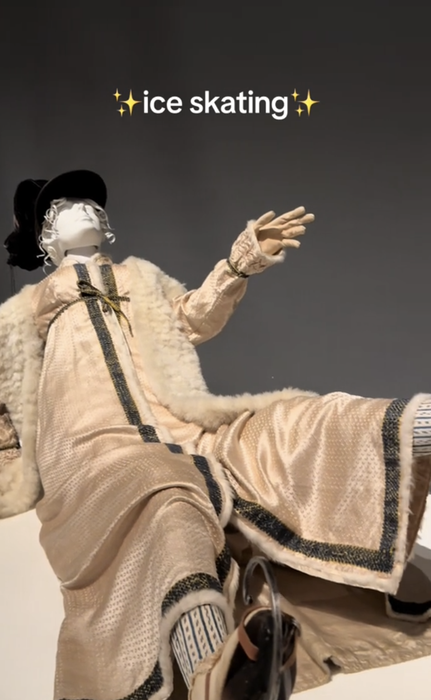 A mannequin dressed in retro-inspired ice skating gear, featuring a long coat, gloves, hat, and boots. Text reads 