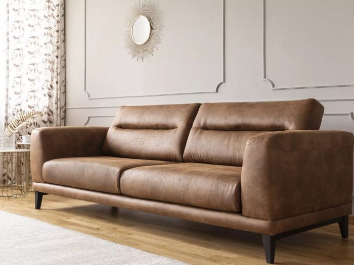 A brown leather sofa positioned in a living room with white walls