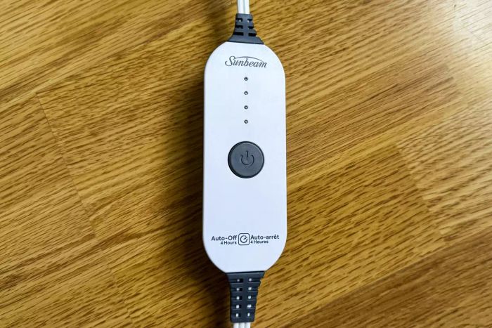 The power button for the Sunbeam Royal Mink Sherpa Heated Blanket, placed on the floor