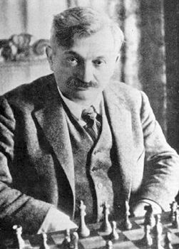 Emanuel Lasker is remembered as one of the most dominant figures in chess history. His 27-year reign as World Champion is the longest in the game’s history, an achievement that solidified his status. Lasker was instrumental in transforming chess into a professional career by negotiating high appearance fees. His rise to prominence began in 1889, and by 1893, he achieved a perfect score of 13/13 in a prestigious New York tournament, one of the few perfect scores in chess history. In 1894, Lasker defeated Wilhelm Steinitz to claim the World Title with a record of 10 wins, 5 losses, and 4 draws, marking the start of his extraordinary reign. Critics claimed he had only beaten an aging champion, but Lasker responded with even stronger performances. He successfully defended his title in 1907 against Frank Marshall without losing a game and then triumphed over his rival Siegbert Tarrasch in 1908 with 8 wins, 5 draws, and 3 losses. Tarrasch blamed his defeat on the weather. In 1910, both Carl Schlechter and Janowsky challenged Lasker for the crown but failed, with Janowsky not winning a single game. In 1911, José Raúl Capablanca attempted a challenge, but Lasker’s tough conditions led to Capablanca’s withdrawal. World War I interrupted further title defenses, and in 1921, Lasker was finally defeated by Capablanca, though by then he was 53 and past his peak. Lasker played no more major matches until 1934, when he joined the Soviet Union and placed 3rd in Moscow at age 66, an achievement dubbed a “biological miracle.” Despite his loss of the World Championship, Lasker often outperformed Capablanca in tournament play, and his natural brilliance, longevity, and influence remained a major inspiration for Russian masters.