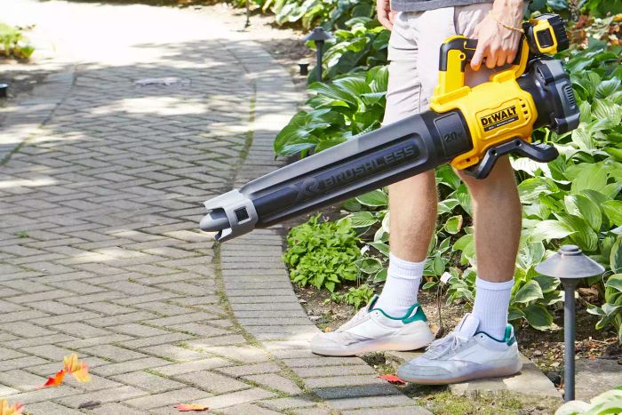 A person using the Dewalt DCBL722P1 20V Max Brushless Cordless Battery-Powered Handheld Leaf Blower