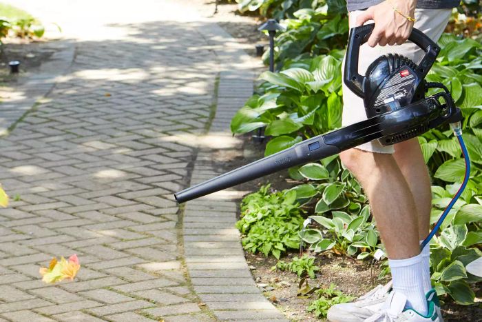 The Toro Power Sweep 160 MPH 155 CFM 7 Amp Electric Leaf Blower is being used to blow leaves off the pavers.