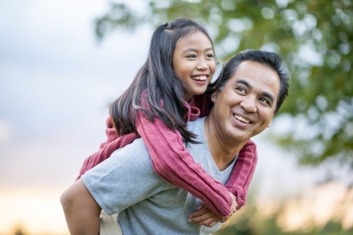 a dad carrying his young daughter on his back