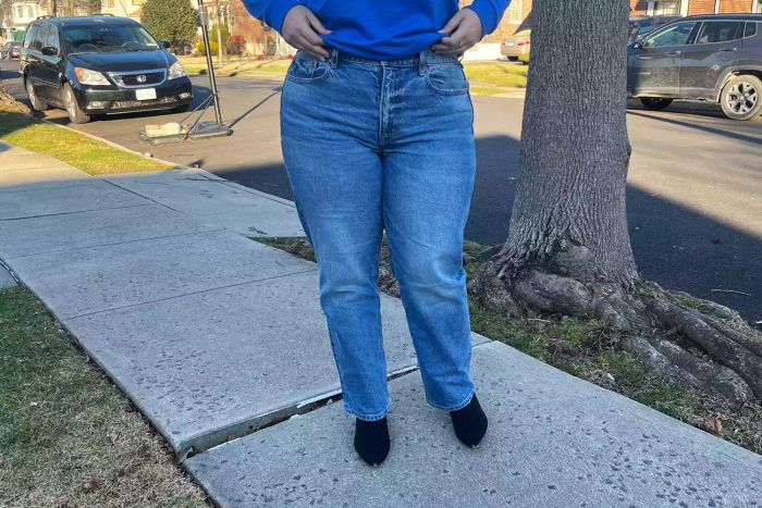 Image shows the front view of a person wearing American Eagle AE Stretch Super High-Waisted Ankle Straight Jeans in an outdoor setting