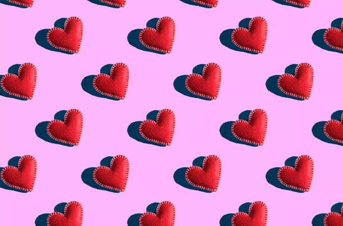 A seamless pattern of red hearts on a soft pink background, representing the spirit of Valentine's Day. A handmade design.