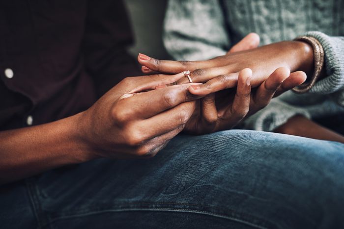 A person placing a ring on someone’s finger.