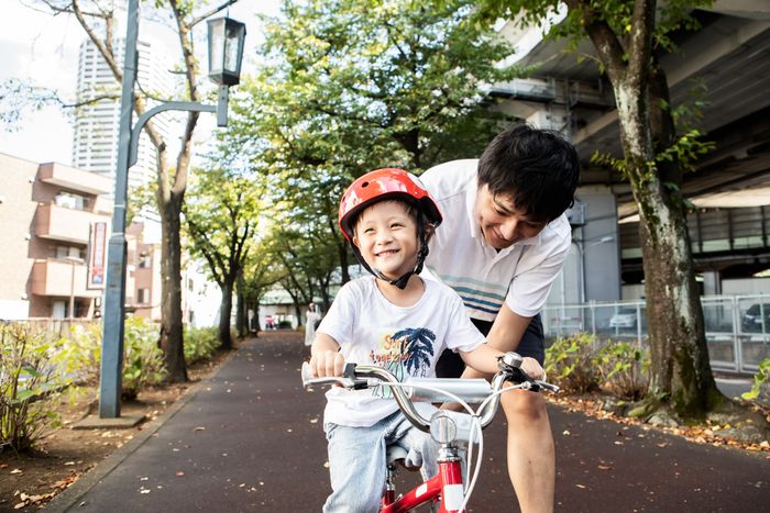 a man assisting a child with riding a bike
