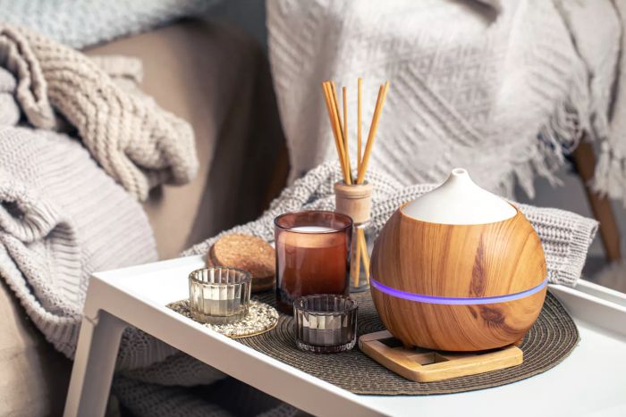 An oil diffuser set against a softly blurred backdrop next to candles. A visual representation of aromatherapy and well-being.