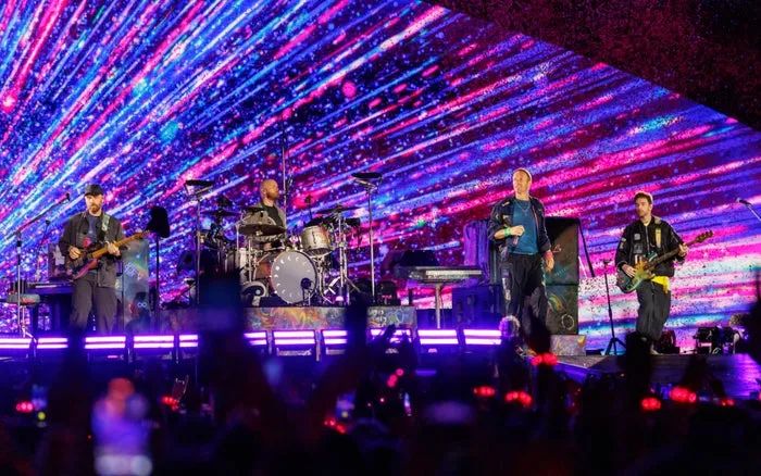 The band takes the stage with a striking, abstract light show in the background, while the audience watches in awe