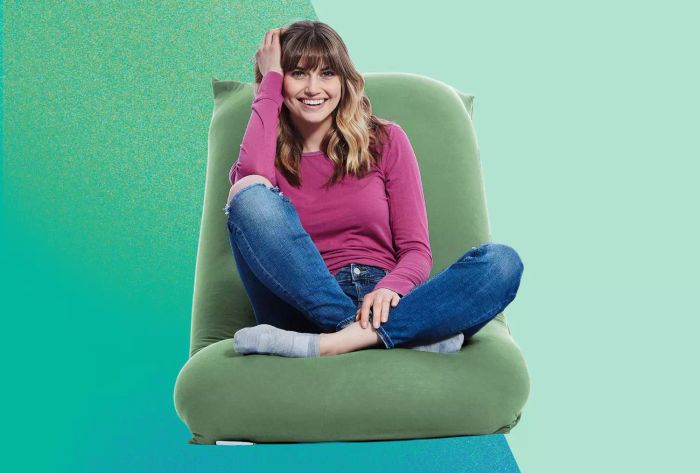 An individual relaxing in the Yogibo Short Bean Bag Chair against a green backdrop