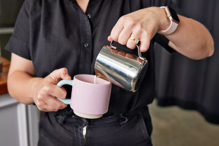 A person is pouring steamed milk into a mug.