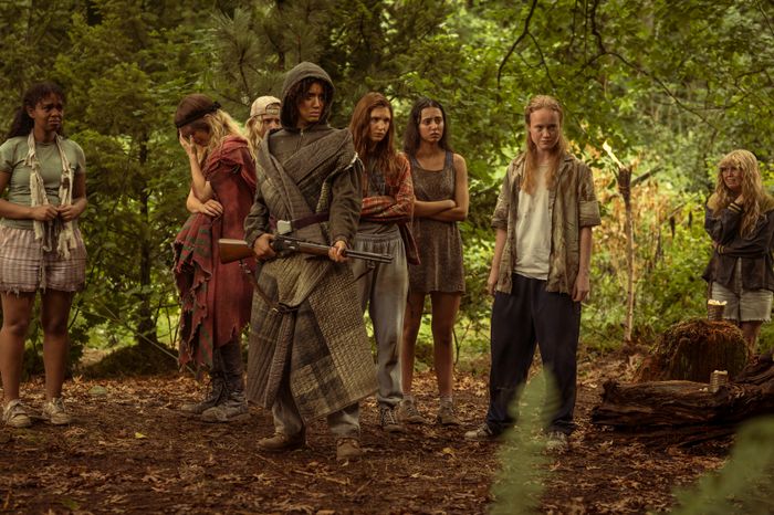 A dramatic scene from 'Yellowjackets' Season 3 showing the group of teenage girls in the woods, exuding an intimidating presence