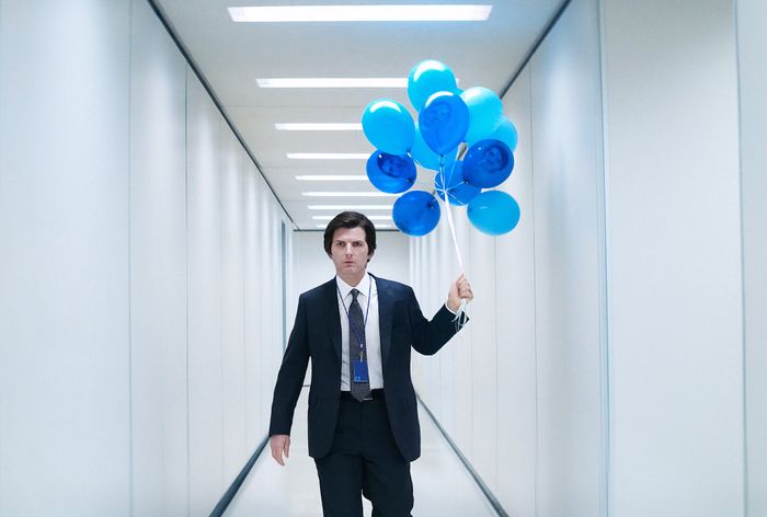 Adam Scott in 'Severance' wearing a suit, walking down a long hallway holding a bunch of blue balloons