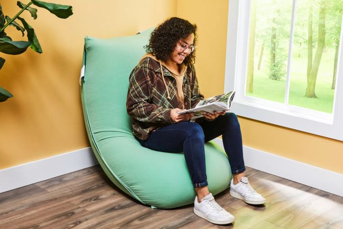 Side view of a person seated on a Yogibo Short Bean Bag Chair, reading a book.