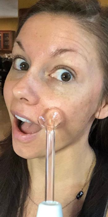 A woman applying a facial skin serum with an applicator to her cheek