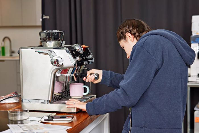 A person is inserting the portafilter into the De'Longhi La Specialista Prestigio Espresso Machine.