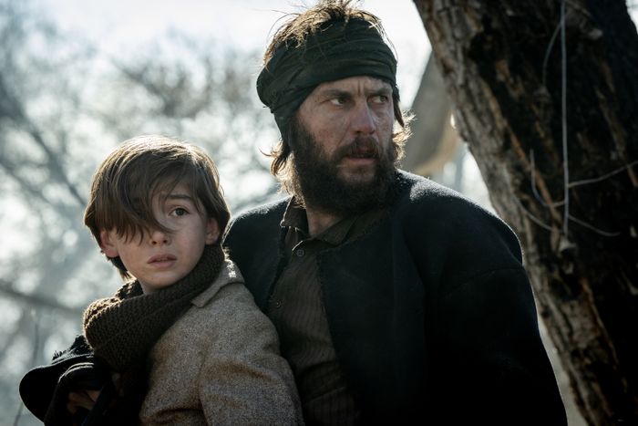 A scene from the period drama featuring a rugged man and a child, both gazing intensely into the distance in an outdoor setting