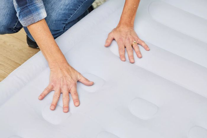 A person is applying pressure to the Simmons Lumbar Firm Full Tri-Zone Air Mattress.