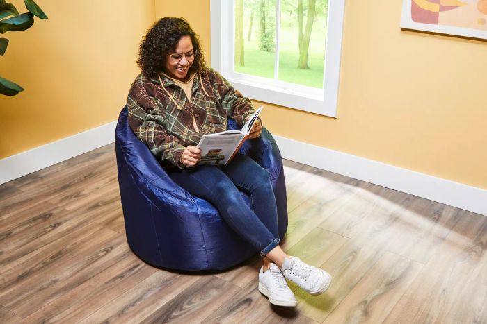 An individual enjoys a relaxing reading session on the Big Joe Milano Bean Bag Chair.