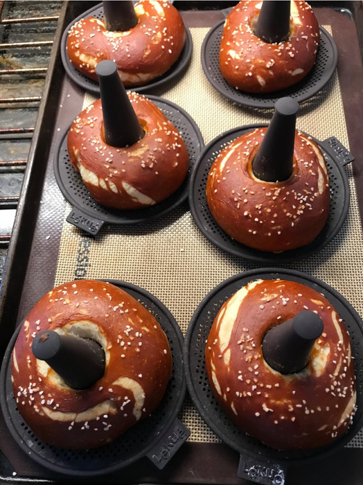 Black silicone mats with raised cones to create perfect holes in six freshly baked pretzel bagels.