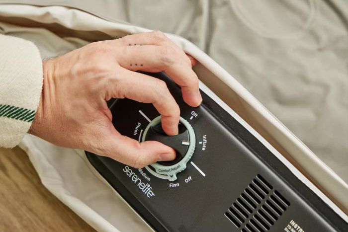 A person is adjusting the dial on the SereneLife Luxury Full-Size Air Mattress with Built-in High-Speed Pump to set firmness.