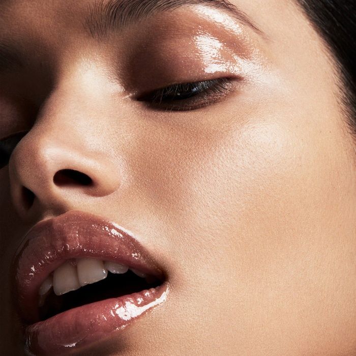 Close-up of a model with a glossy makeup look, featuring shimmering eyeshadow and sparkling lip gloss.